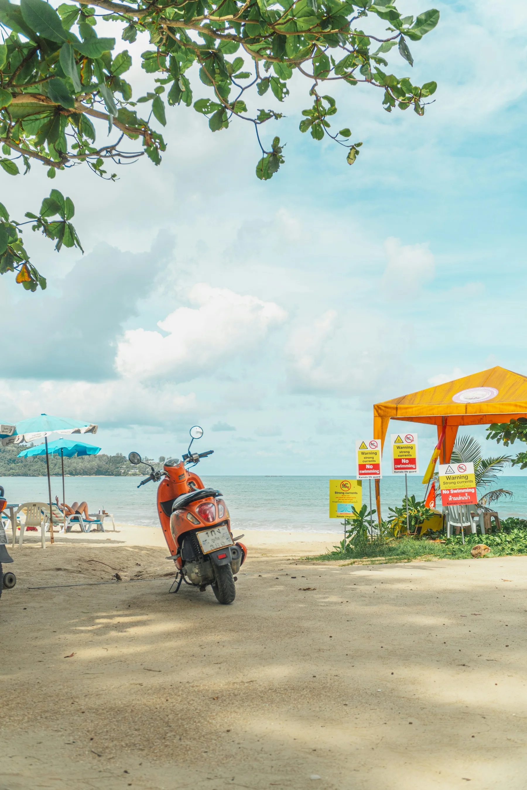 Kamala Beach in Phuket with a parked scooter; illustrative scenery, not rental fleet